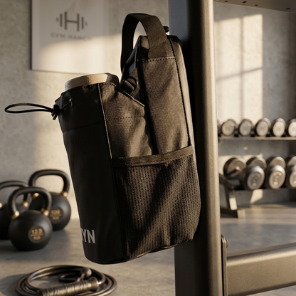 Black gym bag hanging on a barbell in a gym setting with kettlebells and weights in the background.