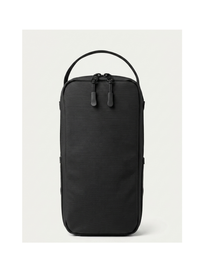 A black textured nylon travel pouch with a top carry handle and dual zipper pulls, shown against a light gray background.