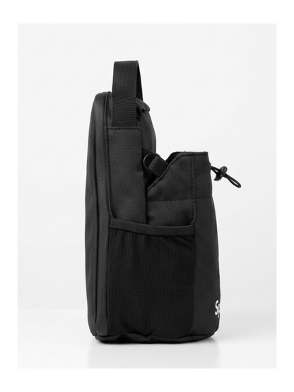 A black nylon shoulder bag shown from the side profile, resting on a white platform against a white studio background.